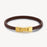 Brown leather bracelet with gold clasp on a white background