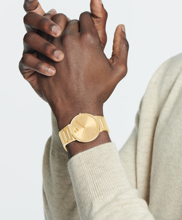 Gold watch on a wrist with a neutral background