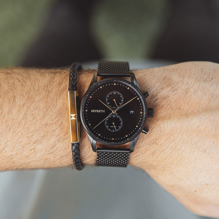 Men's MVMT Voyager Tundra, accented with gold markers, hour, minute and second hands on a balck dial. Dual chronographs with active time keeping features and a date wheel placed at the three o'clock marker. This watch casing sits between a black mesh stainless steel strap perfect for intricate sizing. 