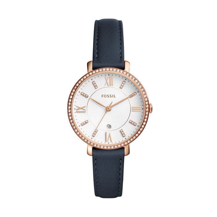 Rose gold-tone stainless steel case with a navy leather strap. Fixed rose gold-tone bezel set with crystals. White dial with rose gold-tone hands and index hour markers. Roman numerals mark the 3, 6, 9 and 12 o'clock positions. Minute markers around the outer rim.