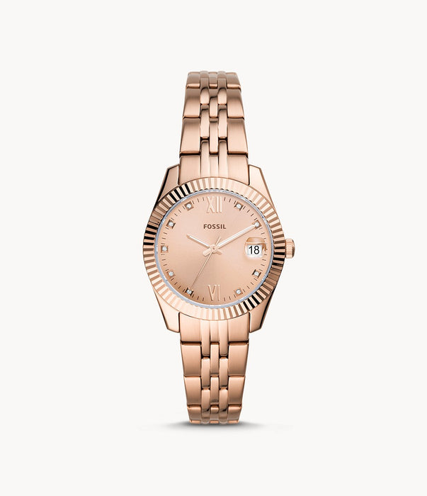 Rose gold-tone stainless steel case and bracelet. Fixed fluted rose gold-tone bezel. Rose gold-tone dial with luminous rose gold-tone hands and crystal hour markers. Roman numerals appear at the 6 and 9 o'clock positions. Minute markers around the outer rim. Dial Type: Analog. Luminescent hands. Date display at the 3 o'clock position.